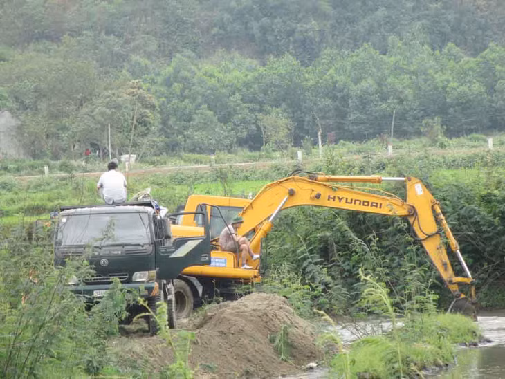 Ô tải và một chiếc máy xúc đang xúc cát
