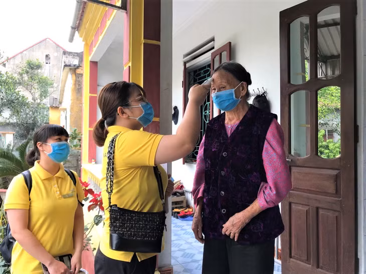 Nhân viên bưu điện TP Uông Bí đo thân nhiệt trước khi phát lương hưu tại nhà cho người dân. 