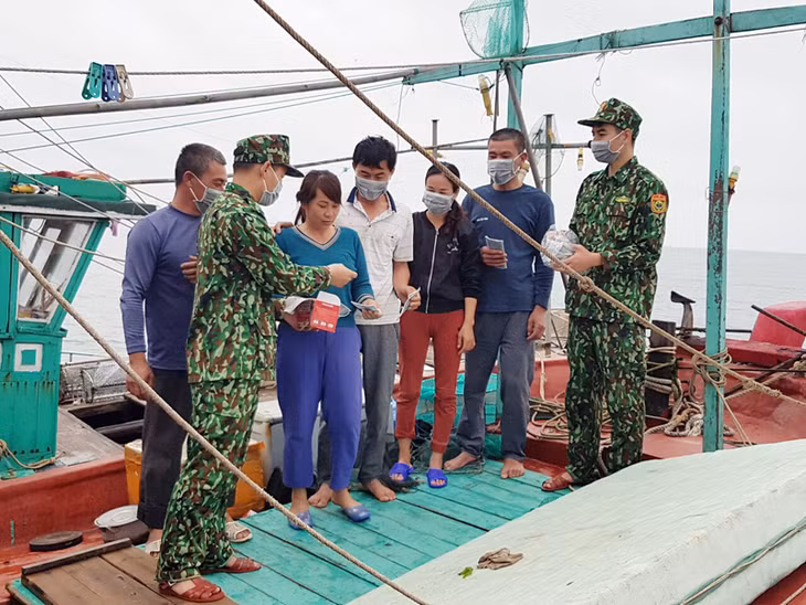 Cán bộ, chiến sỹ Đồn Biên phòng Trà Cổ tuyên truyền, phát khẩu trang y tế cho bà con ngư dân.