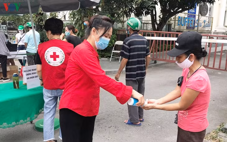  Các tình nguyện viên hướng dẫn người dân sát khuẩn tay và đeo khẩu trang đúng cách.