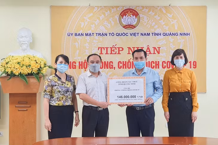 Đại diện Công đoàn Cục thuế tỉnh (trái) trao bảng tượng trưng số tiền ủng hộ Quỹ Phòng, chống dịch Covid-19 cho Ủy ban MTTQ tỉnh.