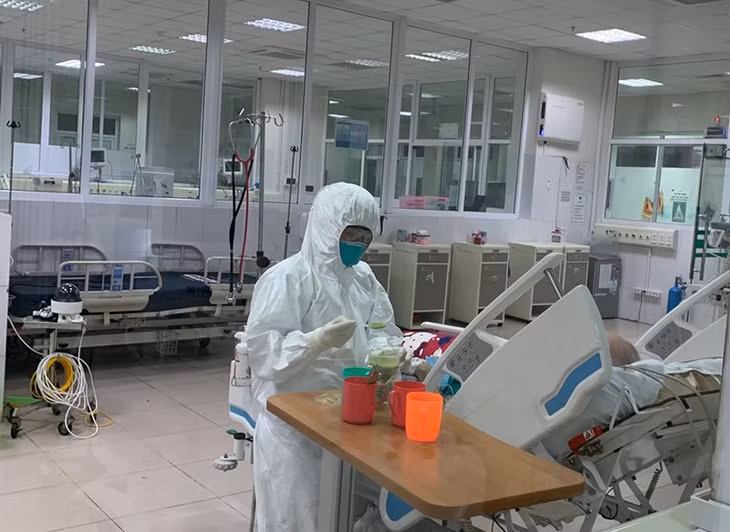 Nhân viên điều dưỡng đang bón từng thìa cháo cho bệnh nhân mắc Covid-19.