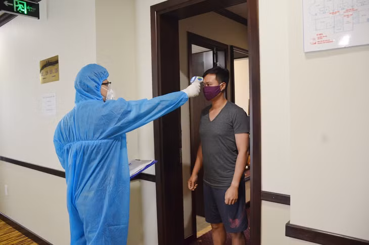 Bác sĩ Hoàng Anh Tuấn, TTYT TP Hạ Long đo thân nhiệt cho người dân tại địa điểm cách ly.