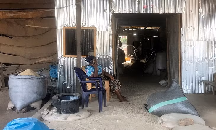 Mercy Yialase ngồi trước xưởng xay xát gạo ở Wurukum trong thành phố Makurdi, bang Benue, Nigeria, hôm 13/4. Ảnh: Reuters.