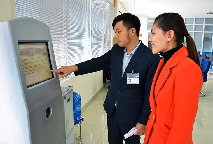 Cán bộ Trung tâm Hành chính công huyện Hải Hà hướng dẫn người dân tra cứu thủ tục hành chính qua kios điện tử.