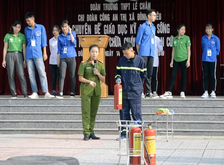 cán bộ PCCC (Công an TX Đông Triều) hướng dẫn kỹ năng sử dụng bình chữa cháy để chữa cháy cho thầy và trò Trường THPT 