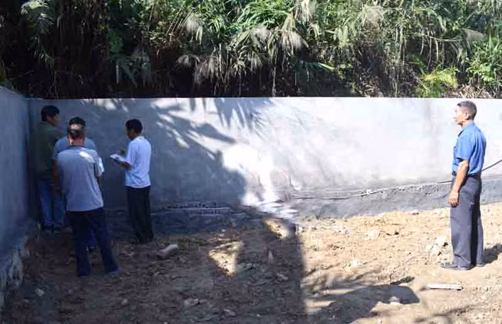 Ông Nguyễn Văn Xèng (bên phải) đang nghiệm thu công trình tường bao nhà văn hóa khu phố 13