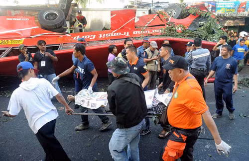 Nhân viên y tế Philippines chuyển thi thể nạn nhân ra khỏi chiếc xe buýt gặp nạn - Ảnh: AFP