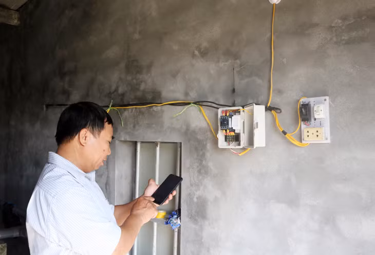Ông Hùng đang vận hành hệ thống tưới văng bằng điện thoại thông minh.