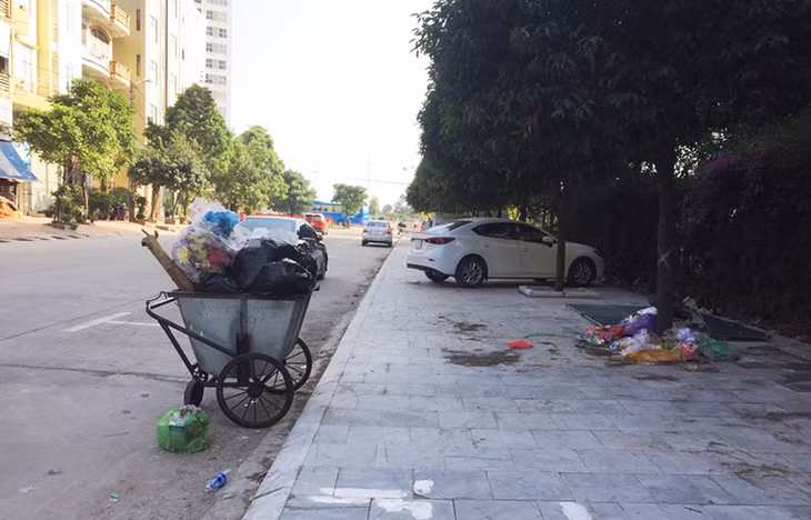 Xe gom rác của khách sạn Galaxy HaLong Hotel đẩy ra sãn chờ xe chở rác đến thu gom, gốc cây cạnh đó thành điểm vứt rác tự phát của người dân. (Ảnh chụp ngày 22/11/2019)
