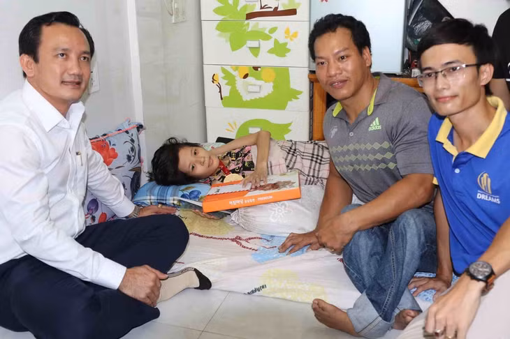 Được chú Công đeo chiếc huân chương vào cổ trước khi trao cho người đấu giá 125 triệu đồng, bé Hương cười vui, dù đang bị đau vì bệnh.