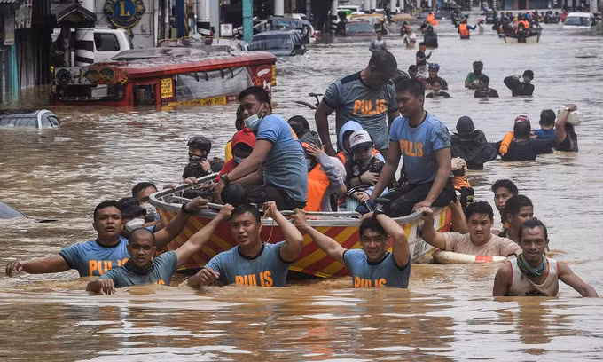Cảnh sát Philippines hỗ trợ người mắc kẹt ở ngoại ô Manila hôm 13/11. Ảnh: AFP.
