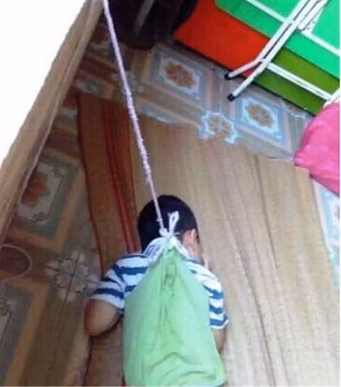 Hình ảnh cháu bé bị buộc dây treo trên cửa sổ.