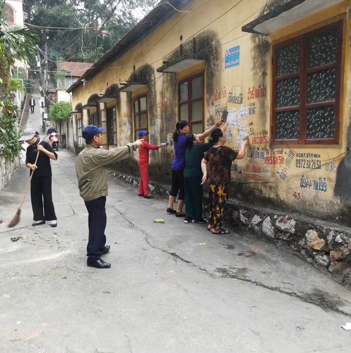 Hội viên phụ nữ Chi hội khu 1, phường Bãi Cháy xóa biển quảng cáo trên tường. 