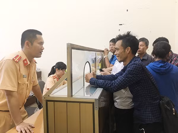Cán bộ CSGT hướng dẫn thủ tục cấp đăng ký phương tiện cho người dân.