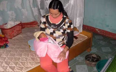 Mất mẹ, bé phải đi bú nhờ chị hàng xóm. Trong phòng vẫn đang còn nồi than đỏ lửa, một thói quen của người dân khi mùa đông giá rét.