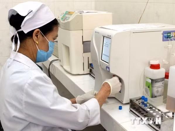Nhân viên y tế sử dụng hệ máy xét nghiệm sinh hóa tự động trong công tác chẩn đoán bệnh. (Ảnh: TTXVN)