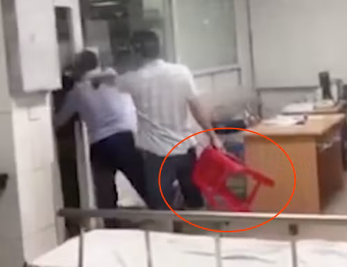 Ông Nguyễn Xuân Huân (người cầm ghế). Ảnh cắt từ video.