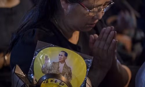 Người phụ nữ chắp tay cầu nguyện khi đoàn rước tro cốt của cố vương Bhumibol Adulyadej đi qua. Ảnh: AFP.