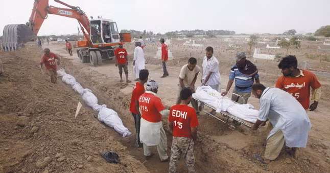 Các tình nguyện viên chôn tập thể nạn nhân nắng nóng tại một nghĩa trang ở Karachi hôm 26-6 - Ảnh: Reuters