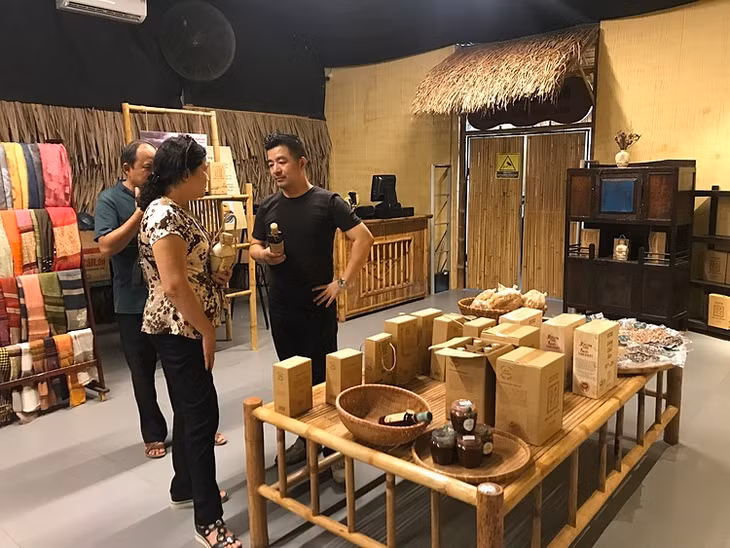 Anh Dũng (áo đen) đang trao đổi với du khách về nước mắm tại khu trưng bày sản vật địa phương tại bảo tàng.