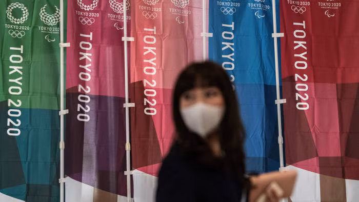 Người dân đeo khẩu trang đi qu những banner Thế vận hội Tokyo 2020 tại Thủ đô Tokyo, Nhật Bản. Ảnh: Reuters