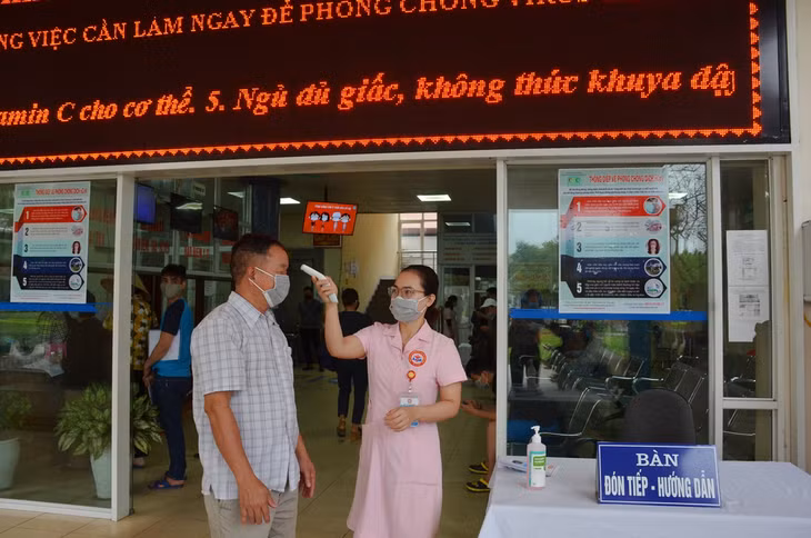 Bộ phận chăm sóc khách hàng hướng dẫn người bệnh đăng ký khám bệnh và kiếm tra thân nhiệt.