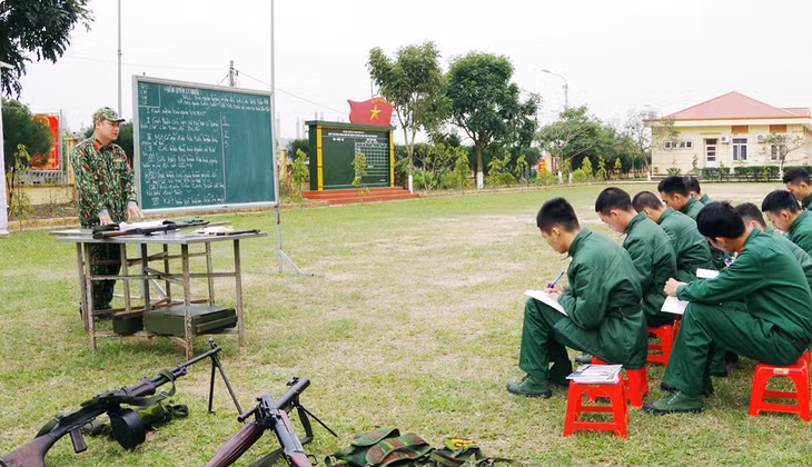 Các chiến sĩ mới chăm chú ghi bài giảng lý thuyết của cán bộ khung trên thao trường 