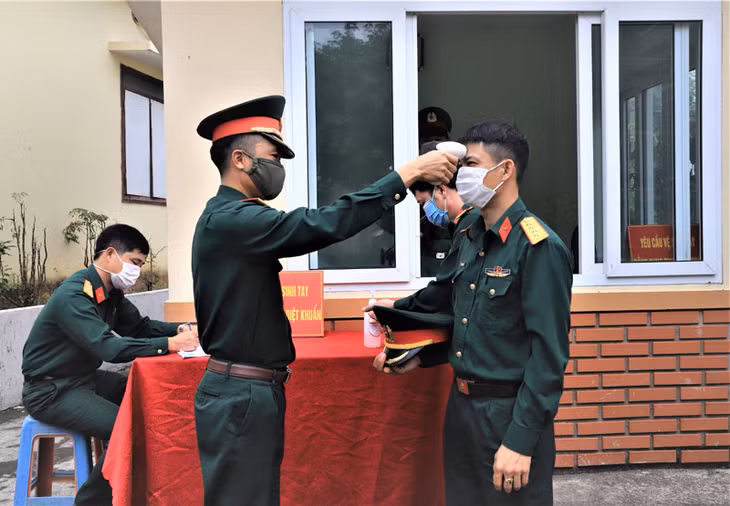 Ảnh 5: Cán bộ, chiến sĩ ban chỉ huy quân sự huyện thực hiện nghiêm việc đeo khẩu trang, đo than nhiệt khi vào đơn vị làm việc.