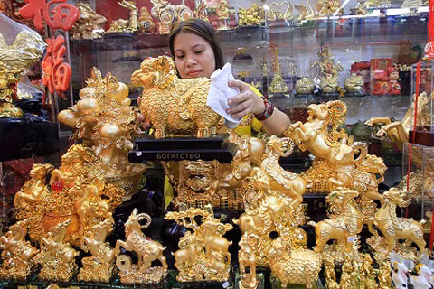 Một người bán hàng ở Minila, Philippines đang lau những bức tượng hình con dê mạ vàng óng ánh. (Ảnh: News)