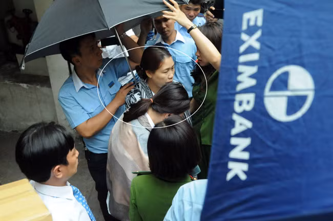 2 nữ cán bộ ngân hàng Eximbank được áp giải ra xe ô tô.