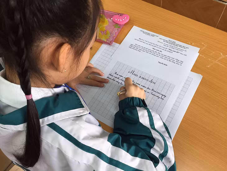Học sinh thi chép lại một đoạn văn trên giấy.