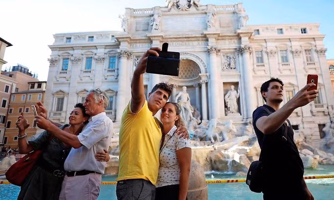 Những người không đeo khẩu trang chụp ảnh trước đài phun nước Trevi ở Rome, Italy, hôm 19/8. Ảnh: Reuters.