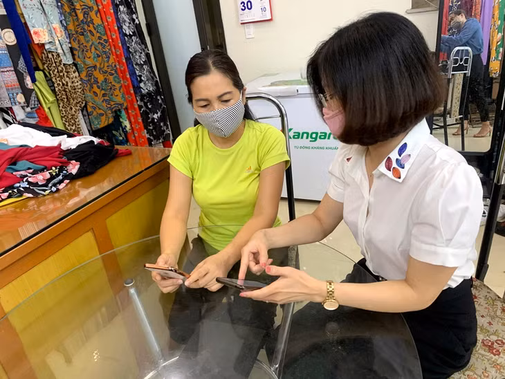 Hội Phụ nữ Phường Bạch Đằng hướng dẫn người dân cài đặt ứng dụng Bluezone. Ảnh: Thu Thảo-CTV