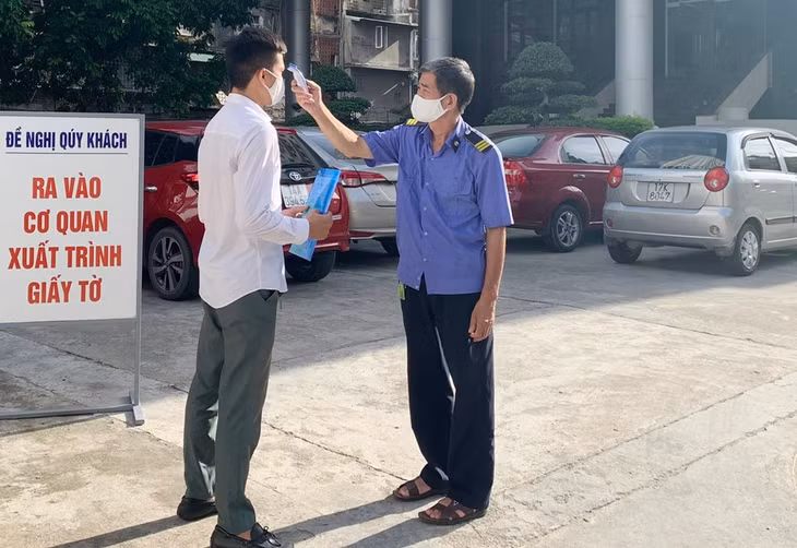 Cán bộ, nhân viên và khách đến làm việc tại cơ quan BHXH tỉnh thực hiện đo thân nhiệt, rửa tay sát khuẩn, đeo khẩu trang.