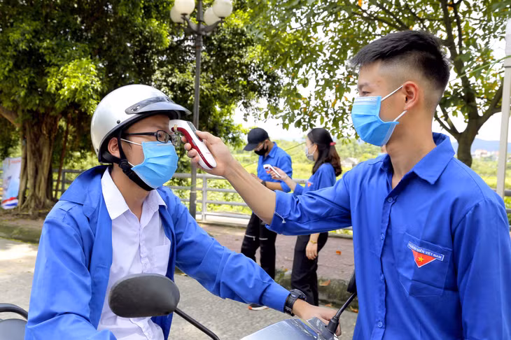 Thanh niên tình nguyện hỗ trợ cán bộ y tế kiểm tra thân nhiệt của các thí sinh, đảm bảo phát hiện nhanh các trường hợp có biểu hiện bất thường về sức khỏe.