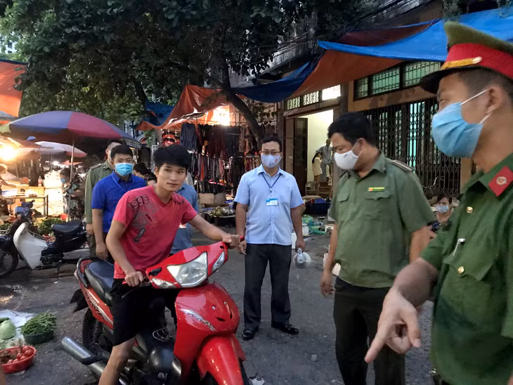 Lực lượng chức năng phường Bạch Đằng nhắc nhở một trường hợp người dân không đeo khẩu trang khi đi chợ.