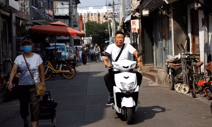 Một người đàn ông không đeo khẩu trang sau khi Bắc Kinh gỡ quy định đeo khẩu trang khi ra đường hôm nay. Ảnh: Reuters.