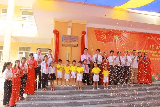 Các đồng chí lãnh đạo thành phố cùng thầy, cô giáo, học sinh gắn biển công trình Trường mầm non Kỳ Thượng (xã Kỳ Thượng). Ảnh: Hoàng Nga. 