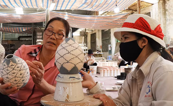 Bà Hà Thị Vinh tận tình chỉ bảo cho một công nhân về kỹ thuật tạo hình sản phẩm.