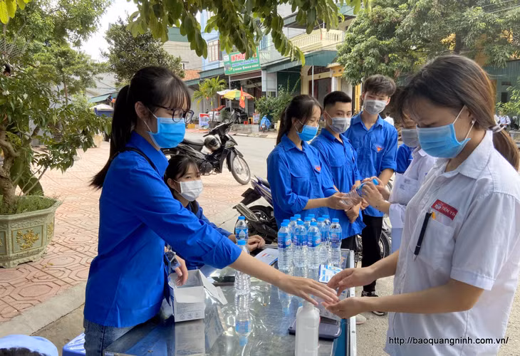 Thanh niên tình nguyện hướng dẫn thí sinh rửa tay bằng dung dịch sát khuẩn trước khi vào khu vực thi.