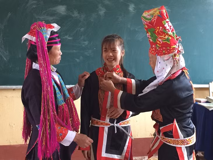 Nghệ nhân Giềng Chống Sếnh xã Quảng Sơn dạy các em học sinh cách mặc bộ sắc phục của người Dao Thanh Y