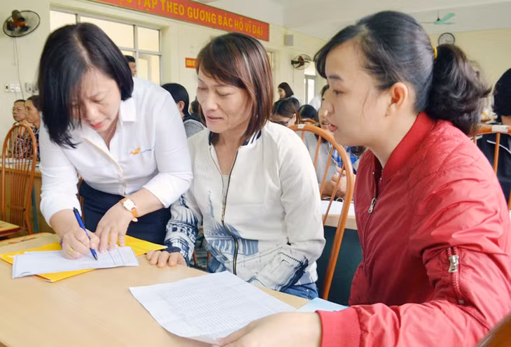 Cán bộ Bưu điện TX Quảng Yên hướng dẫn người dân đăng ký tham gia BHXH tự nguyện. 