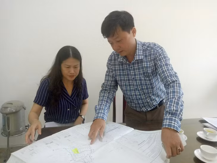 Chủ tịch UBND phường Đức Chính Nguyễn Thị Thu Hằng và cán bộ địa chính phường chỉ cho phóng viên Bản đồ quy hoạch tổng mặt bằng sử dụng đất của Dự án. Ảnh: Thu Nguyệt