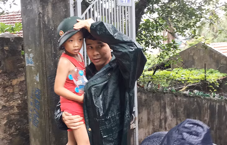 Một em nhỏ được lực lượng quân đôi đưa ra khỏi nhà đi sơ tán.