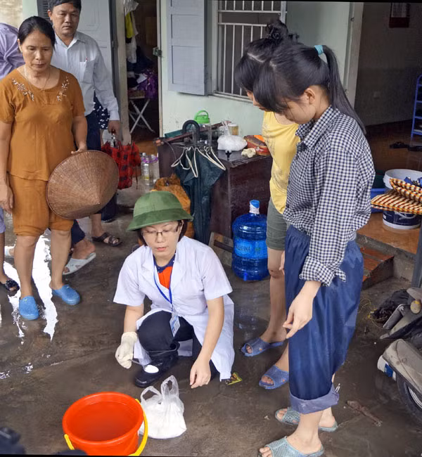 Cán bộ Trạm Y tế phường Cao Thắng hướng dẫn người dân các khu phố sau ngập lụt trên địa bàn phường sử dụng cloramin B khử khuẩn nguồn nước. Ảnh: TT Truyền thông GDSK