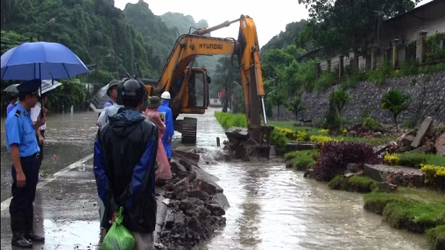 Máy xúc được huy động tạo đường thoát nước ngăn không cho dầu tràn vào nhà dân