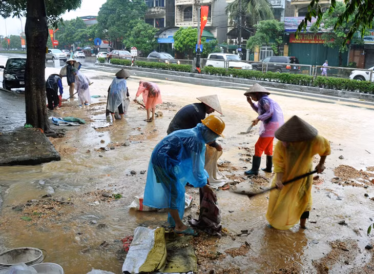 Ngay sau khi nước rút, người dân TP Hạ Long khẩn trương thu dọn đất đá trên đường phố.