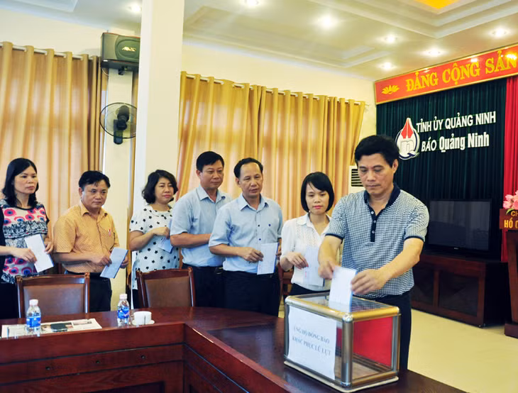 Tập thể lãnh đạo, phóng viên, nhân viên Báo Quảng Ninh ủng hộ người dân khắc phục hậu quả mưa lụt.