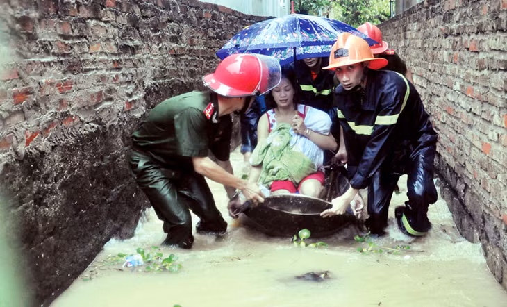 Cảnh sát Phòng cháy chữa cháy tỉnh giúp đưa người dân bị ngập lụt ở tổ 10, khu 1, phường Hà Tu đến nơi an toàn. (Ảnh chụp 10 giờ ngày 28-7-2015). Ảnh: Thái Cảnh